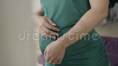 一位孕妇`婴儿的肚子摇晃。 穿绿色衣服的孕妇